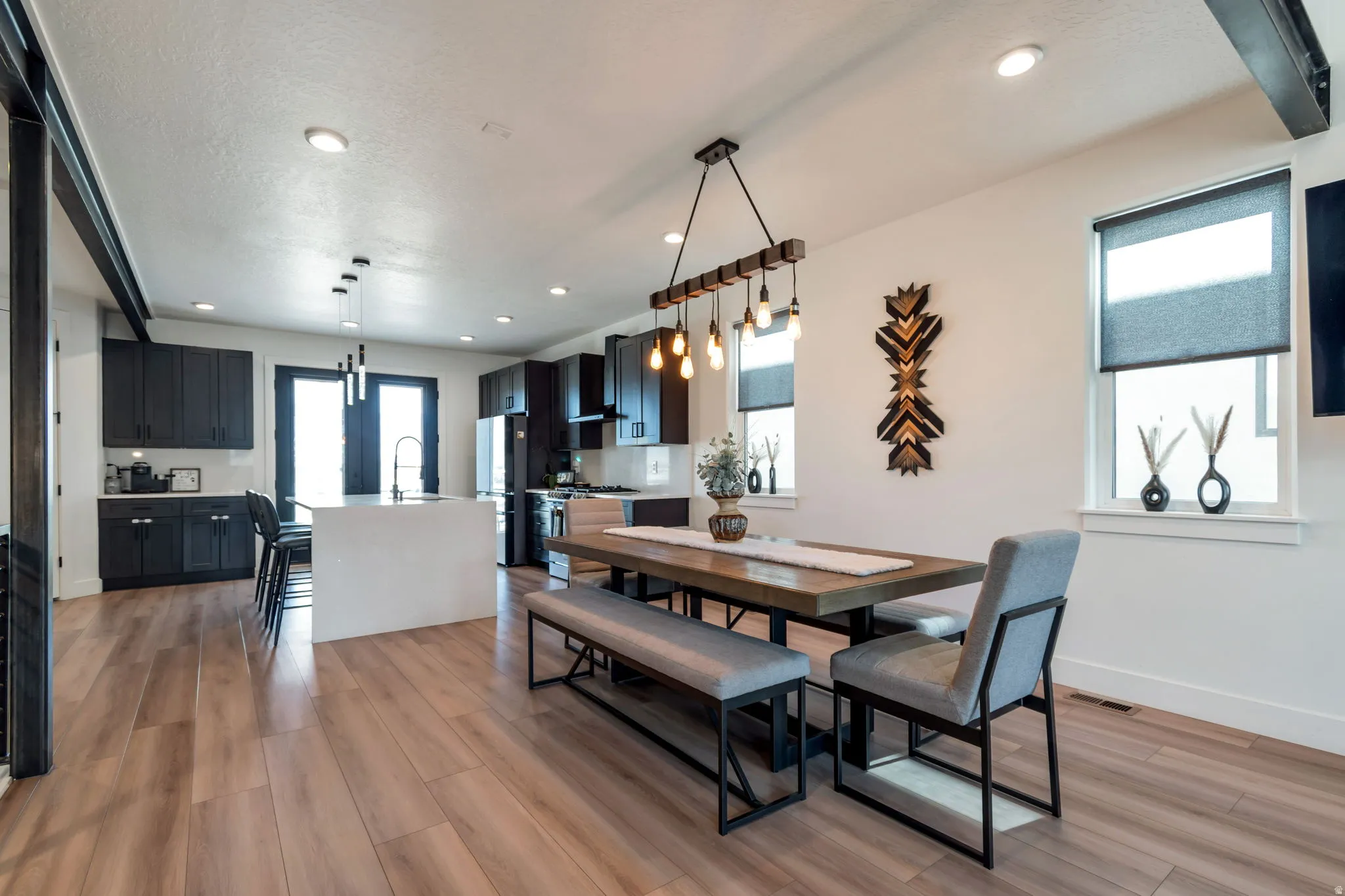 Open-concept living space with wood-finish flooring, dark cabinetry, a kitchen island, and recessed lighting