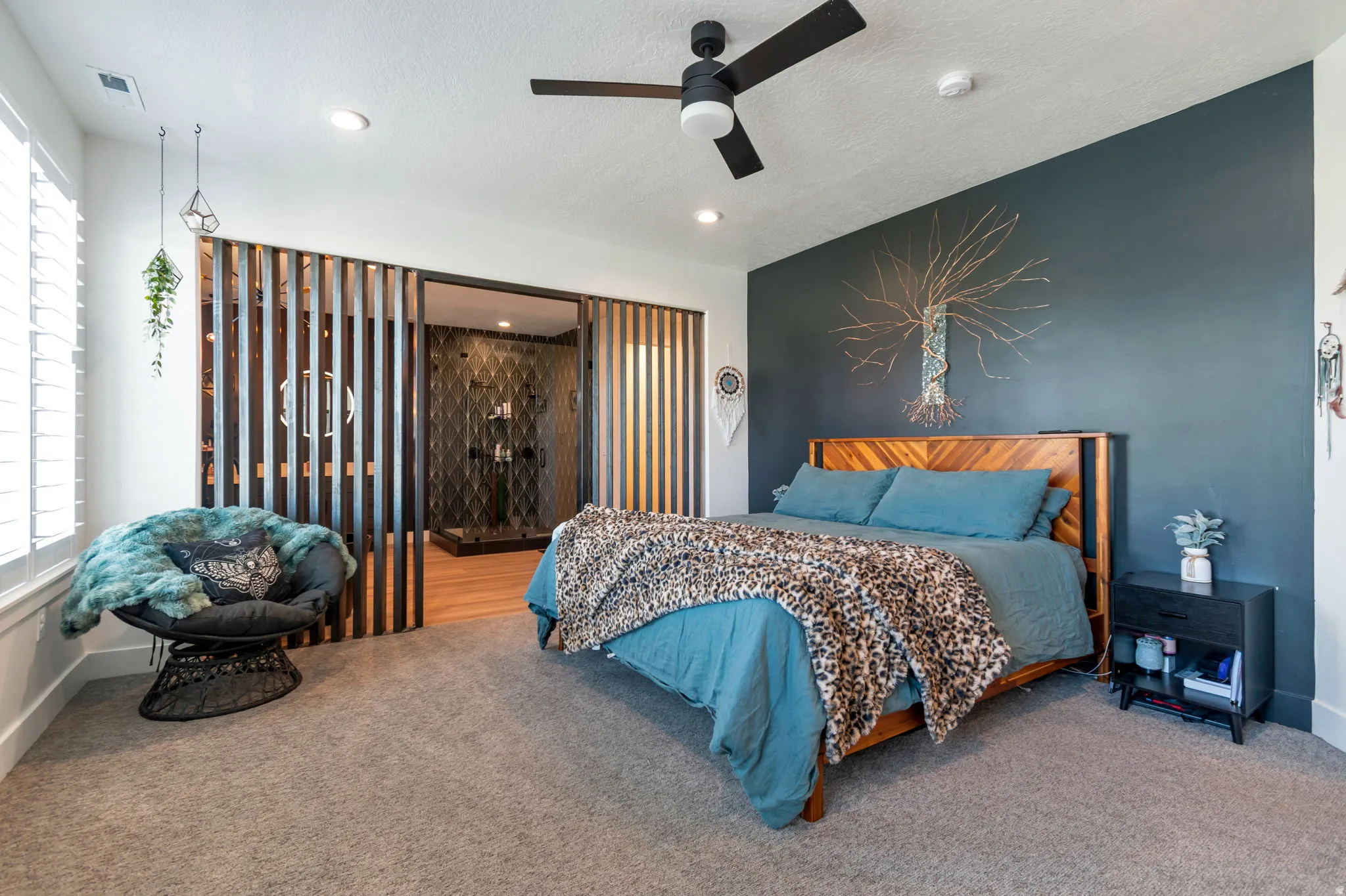 Spacious room with carpet flooring, a dark accent wall, and a ceiling fan