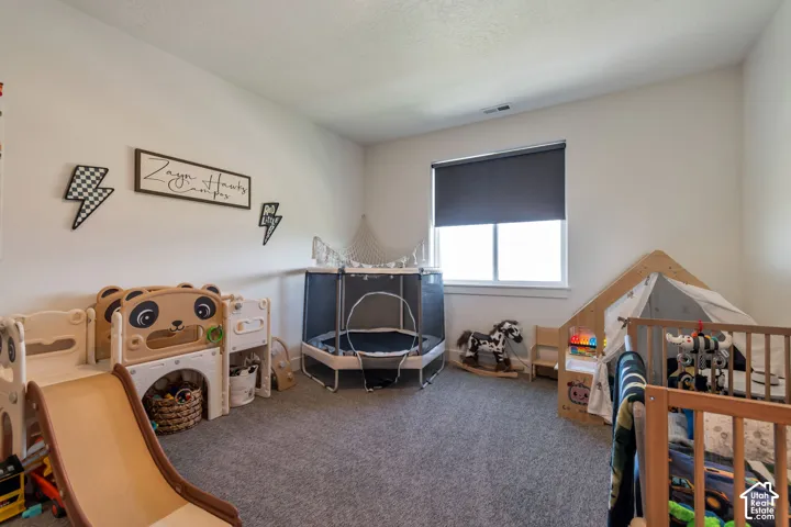 Carpeted room with a single window featuring a roller shade