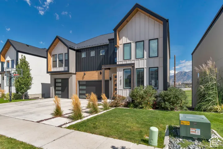 Modern exterior featuring vertical siding, a black metal roof, and a concrete driveway with integrated landscaping