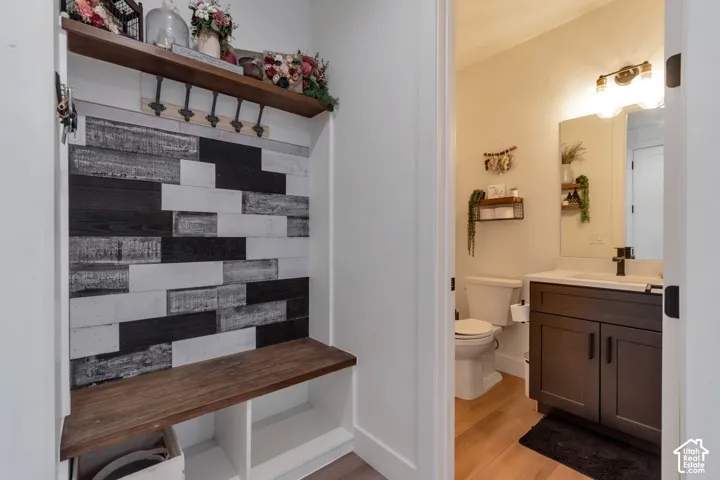 Built-in hall tree with a wood-finish bench and shelf, textured accent wall, and integrated coat hooks