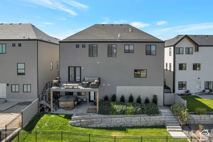 Multi-level backyard featuring a deck with dark railings, a ground-level patio, a tiered retaining wall, and a landscaped garden bed