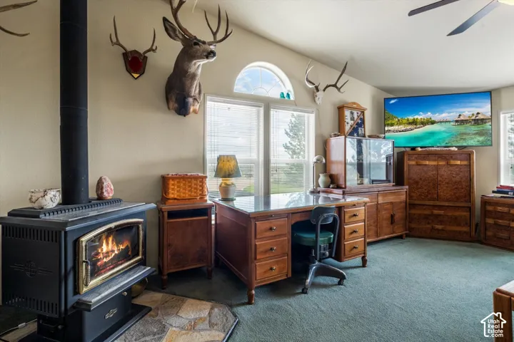 Freestanding black wood-burning stove with stone hearth, vaulted ceiling, and dual windows with an arched transom