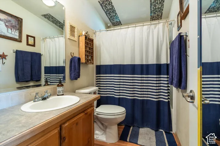 Bathroom featuring a vanity with wood-finish cabinetry, an integrated sink, and a shower/tub combination with a tiled ceiling accent