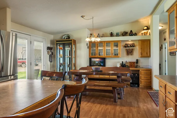 Wood-finish flooring throughout, stainless steel refrigerator, glass-paned French doors, built-in wooden cabinetry with glass inserts, and a functional built-in desk area