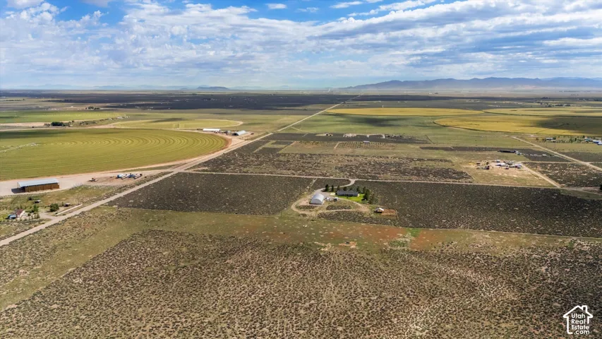 Expansive agricultural landscape featuring open fields, cultivated land, and distant mountain ranges