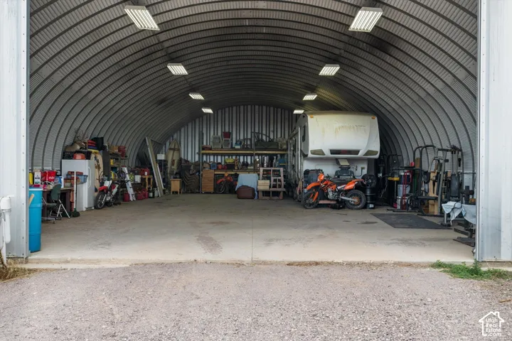 Spacious metal Quonset hut structure featuring an arched roof, concrete flooring, and multiple overhead lighting fixtures
