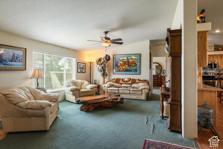 Spacious living area featuring a large window, ceiling fan, and recessed lighting