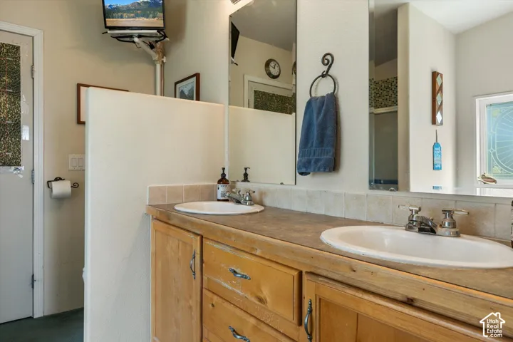 Double vanity featuring integrated sinks, wood-finish cabinetry, and a neutral countertop