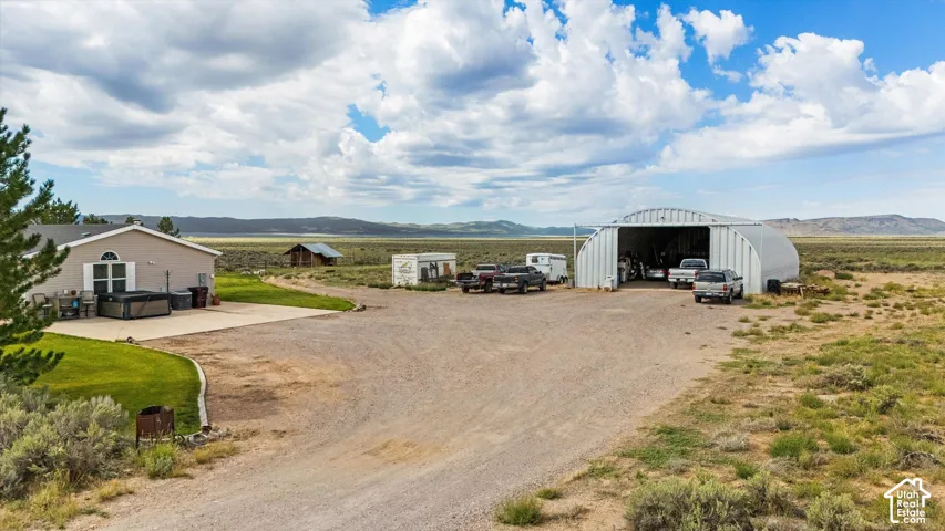 Expansive property featuring a detached metal Quonset-style building, a gravel driveway, a concrete patio, and a manicured lawn area