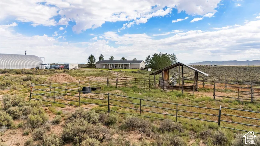 Expansive land with a single-story residence, metal-roofed outbuilding, and a large quonset hut structure