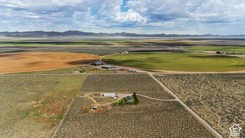 Expansive agricultural land featuring cultivated fields, distinct circular crop patterns, and multiple structures