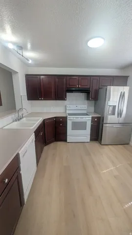 Dark wood-finish cabinetry with white appliances and stainless steel refrigerator