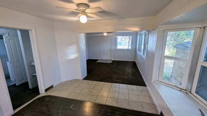 Tiled flooring, multiple windows, ceiling fan, and white painted walls