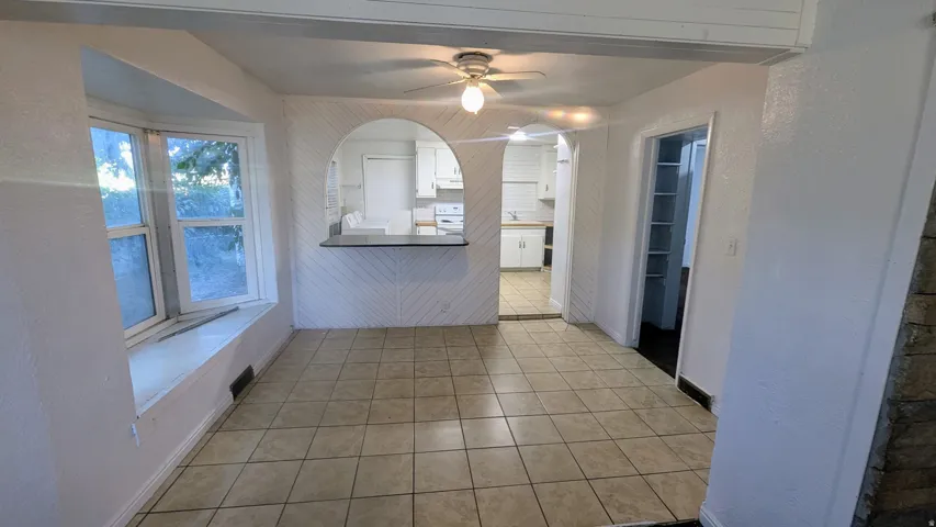 Tiled flooring, bay window with integrated sill, arched pass-through window, and ceiling fan with light fixture