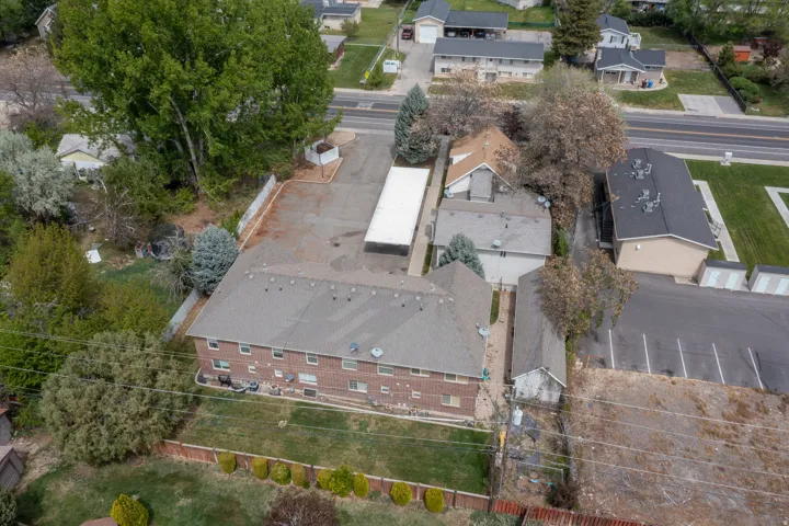 Two-story brick building with multiple units, expansive paved parking area, and a separate covered parking structure