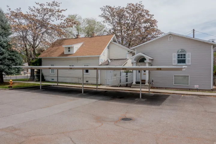 Covered carport parking, two separate building structures, gabled roofline, dormer window, arched window with shutters