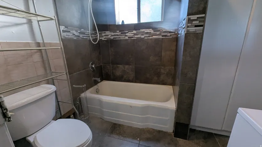 Ceramic tile flooring, full tile surround shower/tub combo, mosaic tile accent band, and a single-pane window