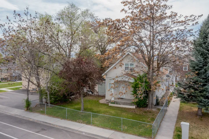 Two-story exterior with a covered porch, chain link fence, and mature trees