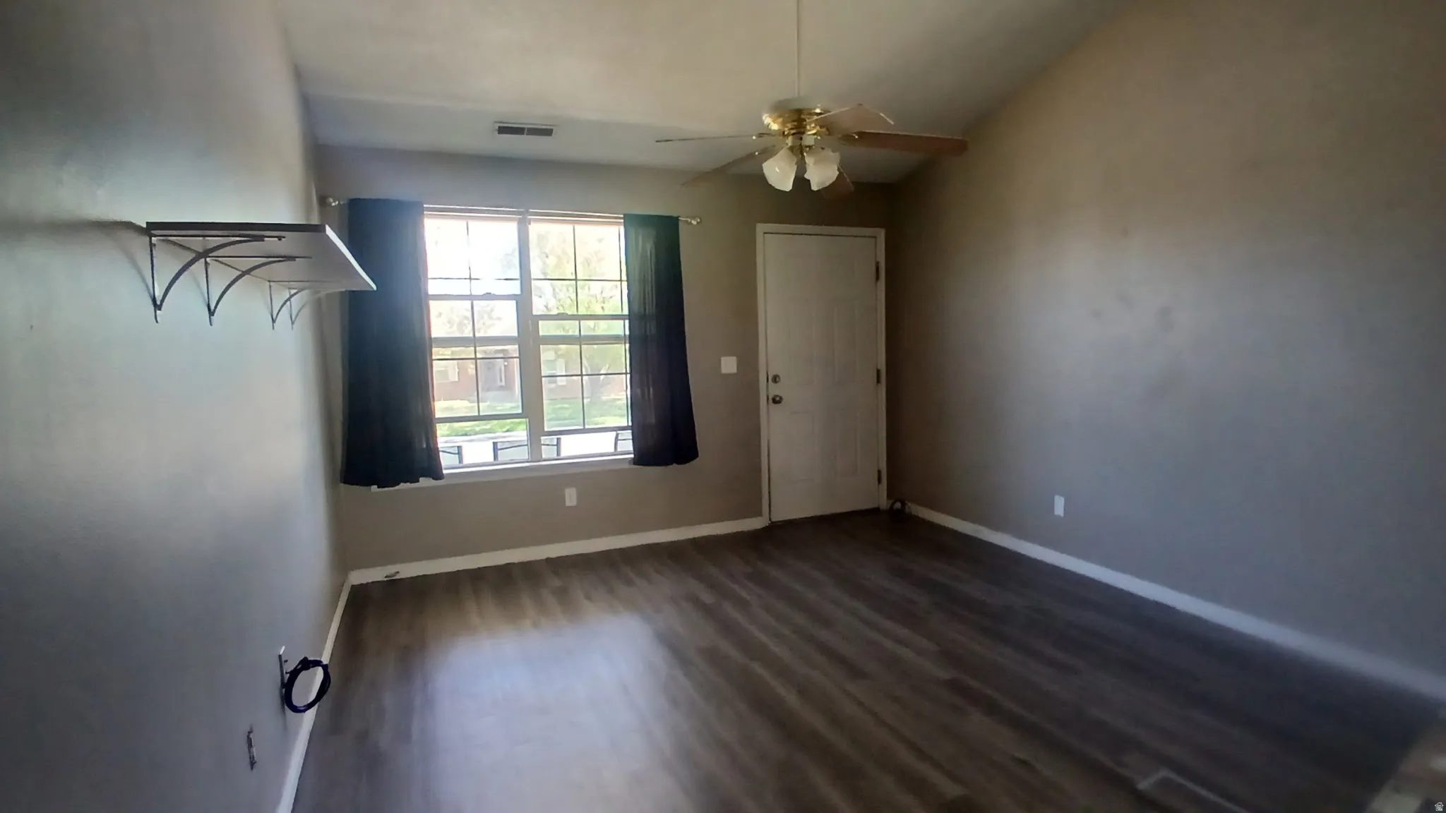 Vaulted ceiling, wood-finish flooring, ceiling fan, large window, and built-in shelving
