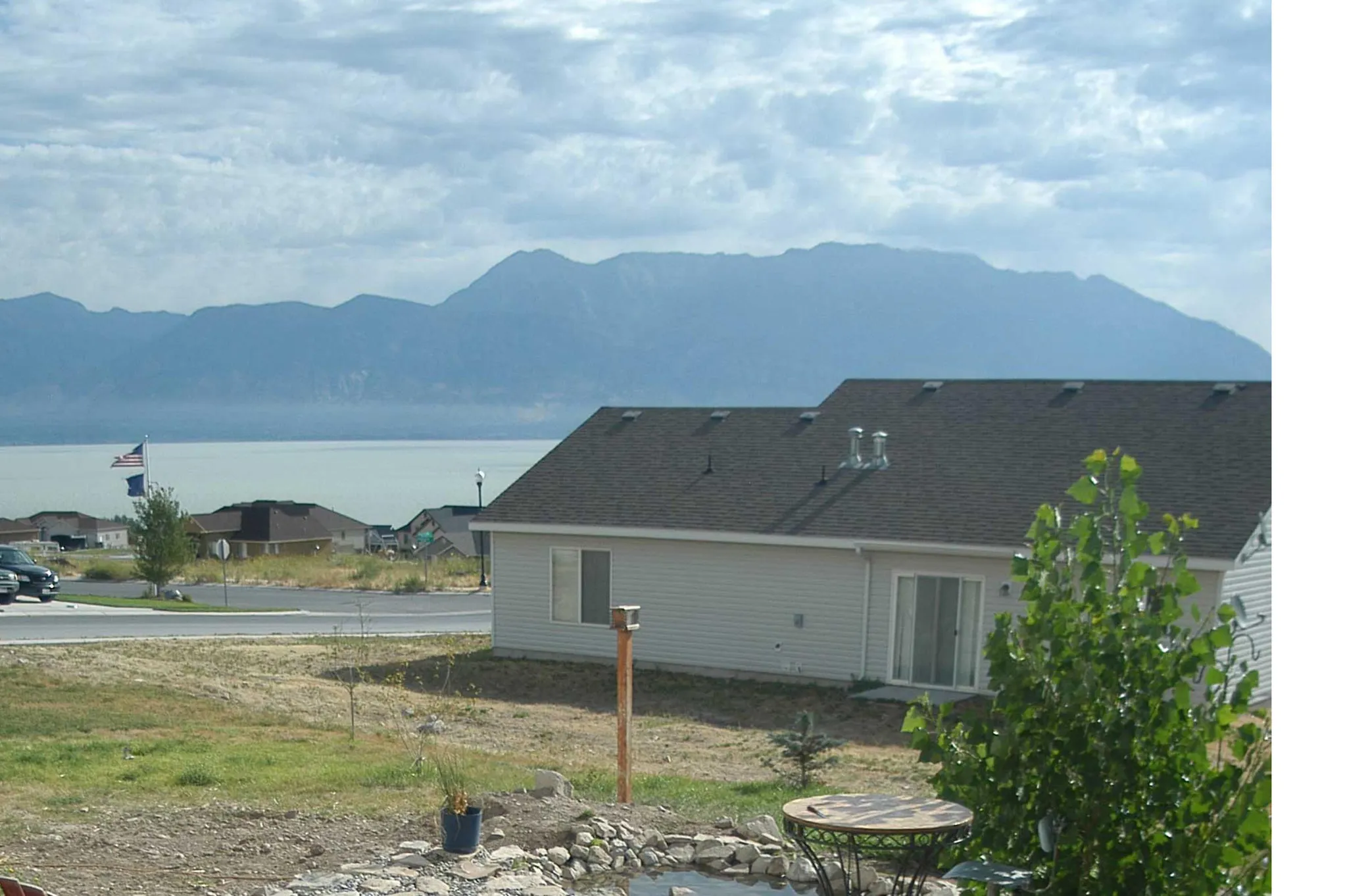 Rear exterior with sliding glass door, mature tree, and partial hardscaping
