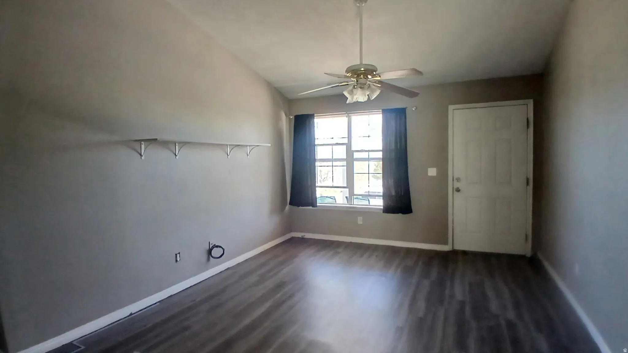 Vaulted ceiling with a ceiling fan, wood-finish flooring, built-in shelving, and a prominent window