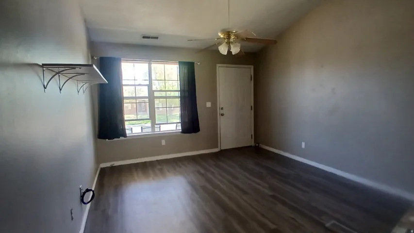 Vaulted ceiling, wood-finish flooring, ceiling fan, large window, and built-in shelving