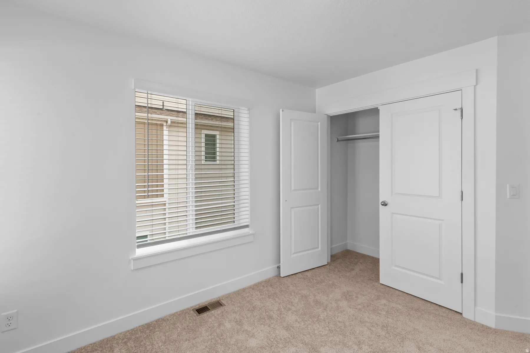 Carpeted flooring, white walls, and a window with blinds