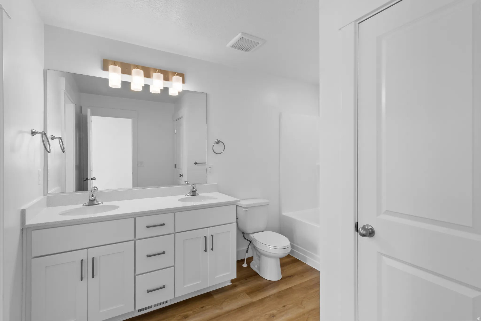 Dual vanity with white shaker-style cabinetry, chrome hardware, and a large integrated mirror