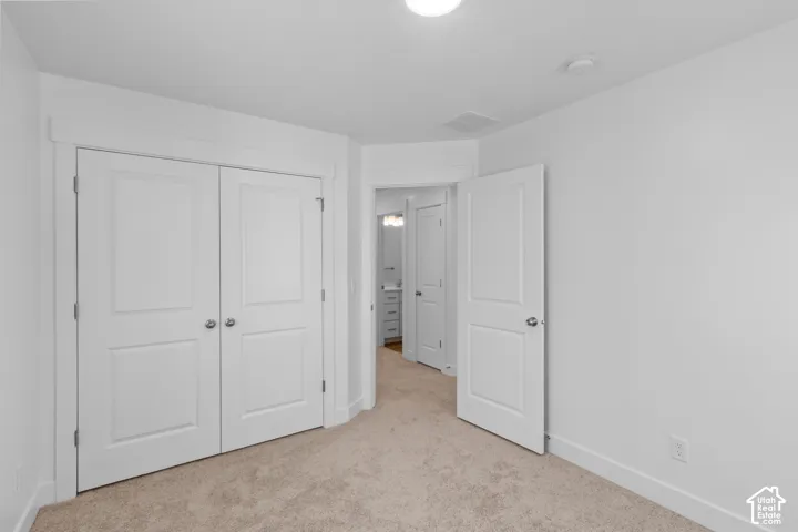 Neutral wall paint with carpet flooring, a two-panel solid core door, and bi-fold closet doors