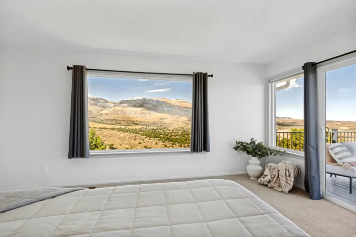 Expansive windows providing abundant natural light, mountain scenery, and direct access to an exterior deck