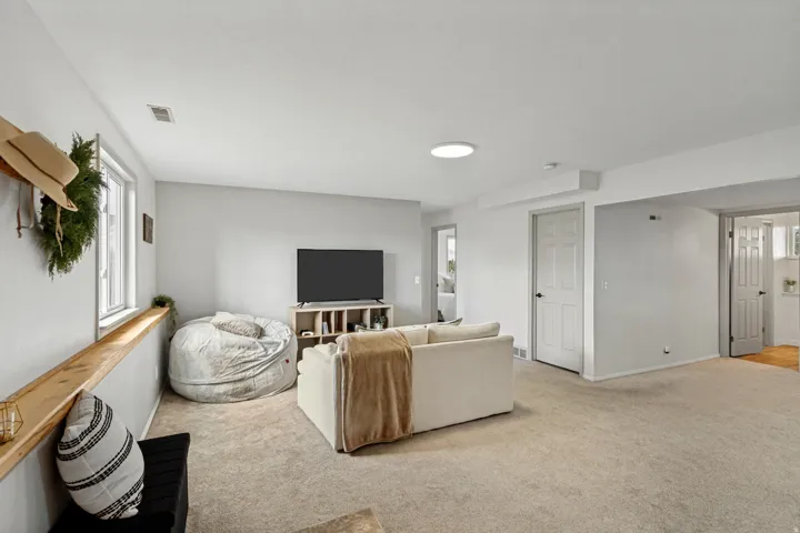 Carpeted living area featuring a built-in wood shelf, white trim windows, recessed lighting, and white paneled doors