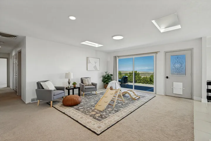 Sliding glass doors opening to an outdoor area, skylights, recessed lighting, and a neutral wall color