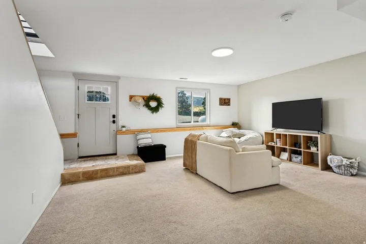 Carpeted living space with a wood-finish window ledge, a paneled door with glass inserts, and recessed ceiling lighting