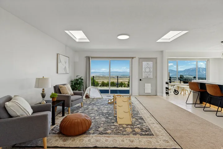 Bright living area featuring skylights, sliding glass door access to an outdoor deck, large picture windows, and wood-finish flooring