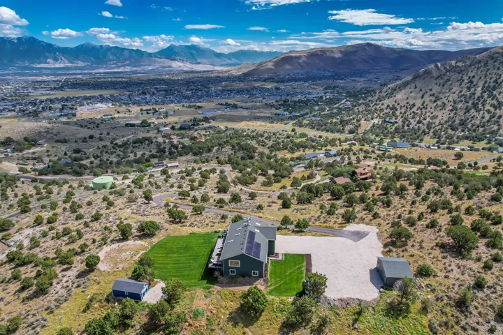 Expansive property with a green lawn, gravel driveway, and solar panels