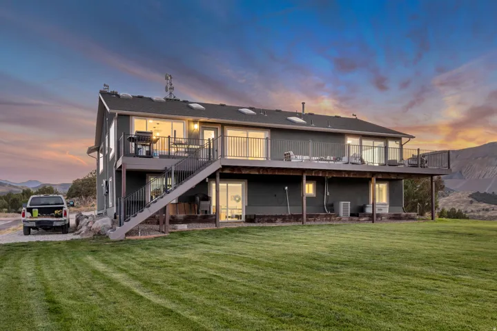 Two-story residence featuring a large upper-level deck with metal railings and an exterior staircase