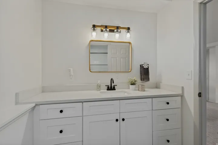 White shaker-style cabinetry with black hardware, an undermount sink, and a countertop