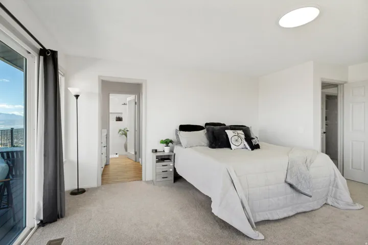 White walls, light-colored carpeting, recessed ceiling light, and a sliding glass door with balcony access