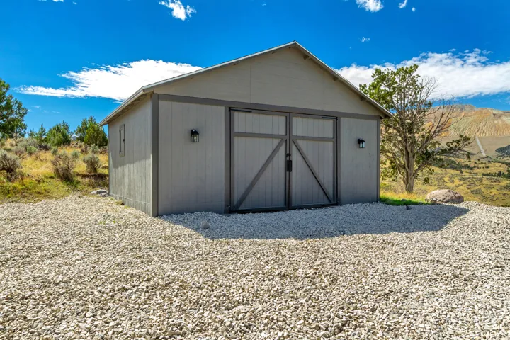 Exterior barn structure with a gable roof, board-and-batten siding, and two barn-style doors