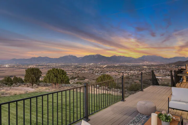 Expansive outdoor deck with composite decking, black metal railings, and a prominent mountain range backdrop