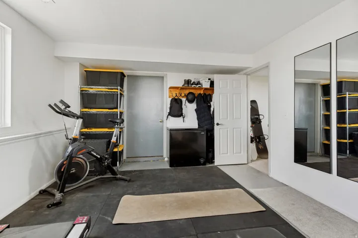 Recessed lighting illuminates the space, featuring durable rubber flooring, a built-in wall rack, and full-length wall-mounted mirrors