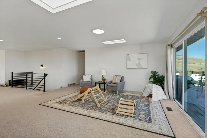Recessed lighting, multiple skylights, black metal railing, and expansive glass sliding doors