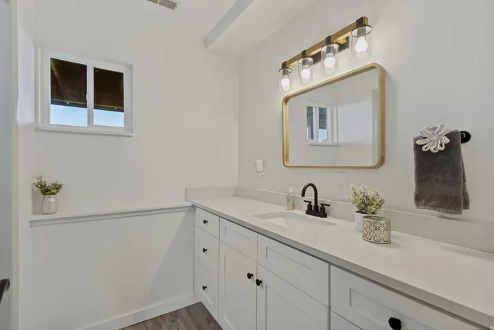 White cabinetry with black hardware, integrated vanity sink, and light-toned countertop