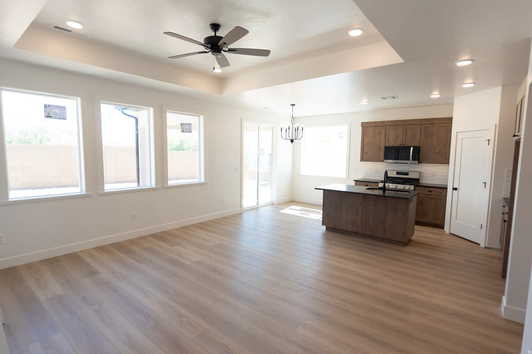 Spacious open-concept living area featuring wood-finish flooring, a tray ceiling, and recessed lighting
