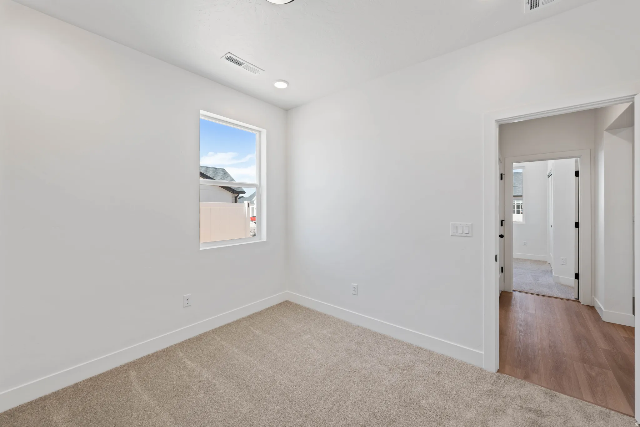 Recessed lighting fixtures illuminate this room with carpet flooring