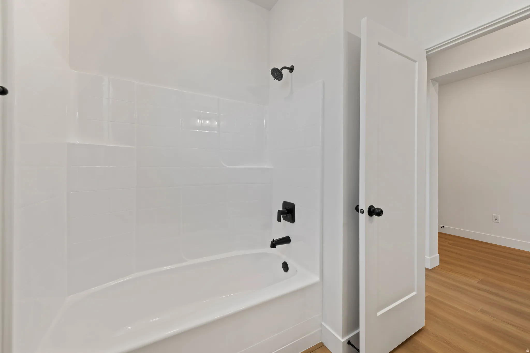 White subway tile surround with integrated shelving, matte black fixtures, and a soaking tub