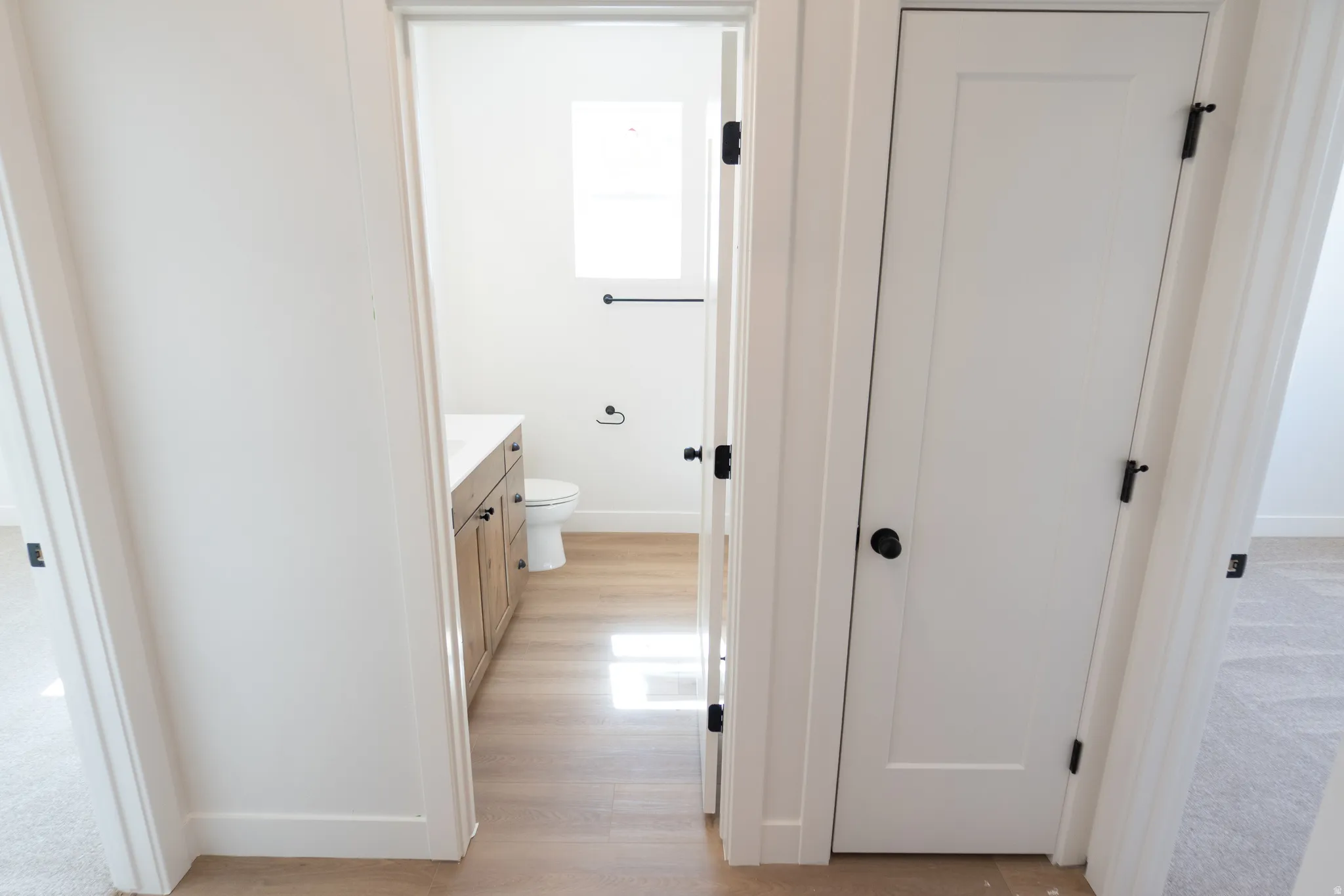 Bathroom featuring wood-finish flooring, a wood vanity with a white countertop, and a white toilet