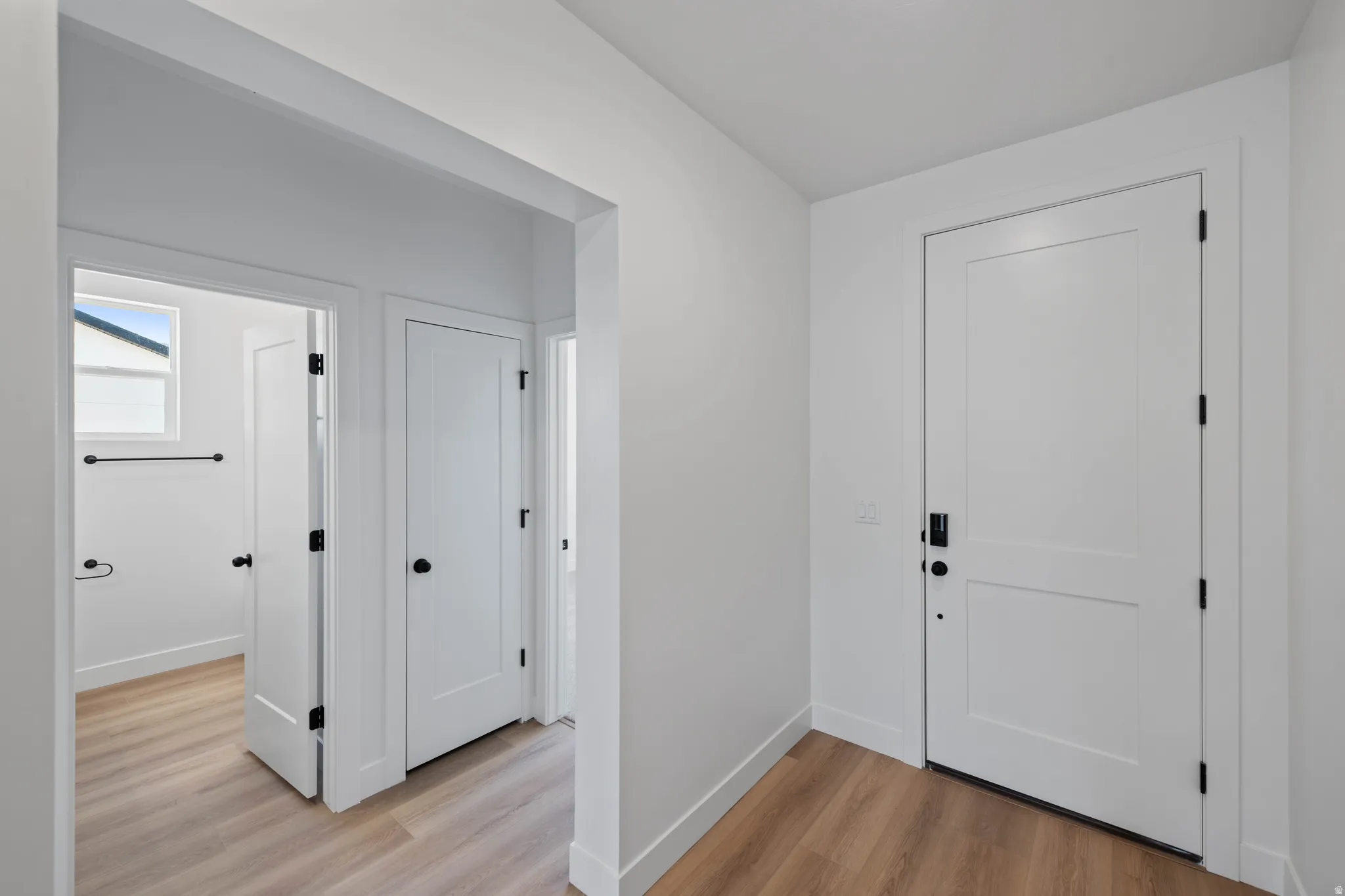 Wood-finish flooring throughout, white interior doors with matte black hardware, and crisp white walls