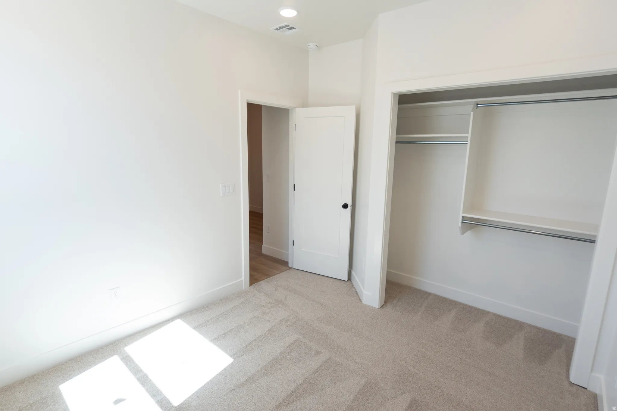 Recessed ceiling lighting, white interior doors with black hardware, neutral wall tones, textured carpet flooring, and a built-in closet system